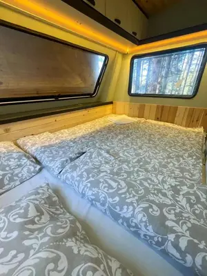a bed in a small room with two windows at Къмпинг Alino Lake in Alino