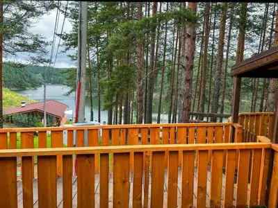 a wooden deck with a view of a river and trees at Къмпинг Alino Lake in Alino