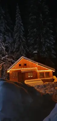 a large wooden cabin with snow on it at night at Вила Рози, Семково in Semkovo