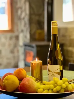 a plate of fruit with a bottle of wine and a candle at Вила Рози, Семково in Semkovo