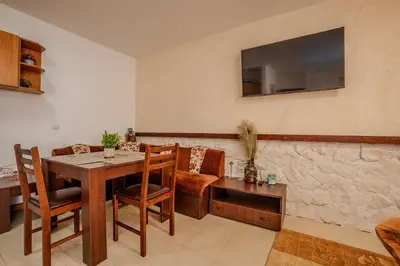a dining room with a table and a tv on the wall at Holiday home with indoor fireplace in Pamporovo