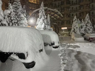 a snow covered car parked in front of a building at SnowLine Flora in Borovets
