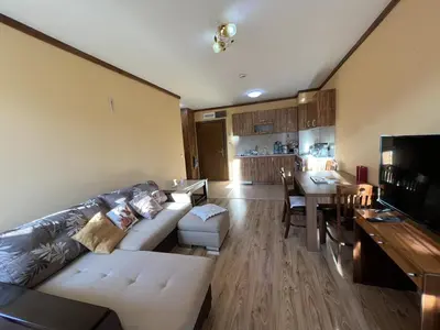 a living room with a white couch and a kitchen at Zweizimmerwohnung mit Bergblick in Bansko