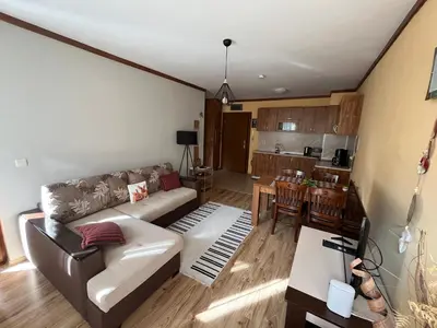 a living room with a couch and a kitchen at Zweizimmerwohnung mit Bergblick in Bansko