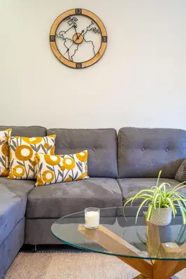 a living room with a couch with a clock on the wall at Lotus apartments with free parking in Sofia