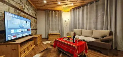 a living room with a couch and a large screen television at Rhodopski Apartment in Chepelare