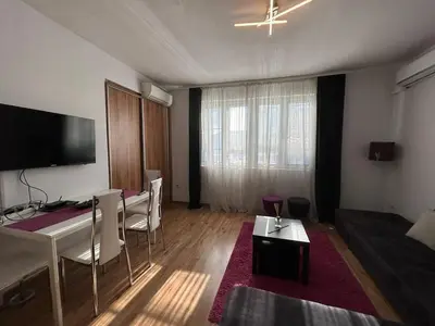 a living room with a table and chairs and a television at Cozy Stay Sofia Historic Center in Sofia