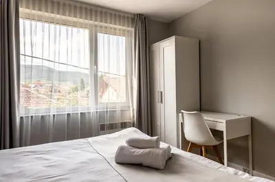 a bedroom with a bed and a desk and a window at Апартамент с люлка и гледка в The House с Термална зона in Velingrad