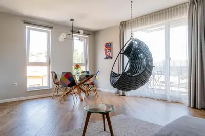 a living room with a table and a swing at Апартамент с люлка и гледка в The House с Термална зона in Velingrad