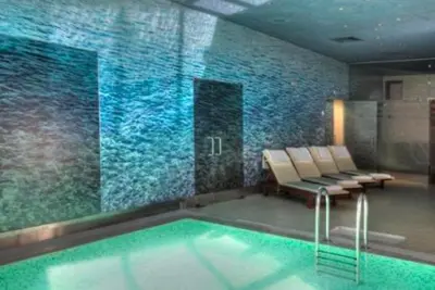 a swimming pool with chairs and a wall of water at Alpine Charm Borovets Apart in Borovets