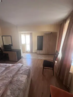 a bedroom with a bed and a chair in a room at Hotel MERIDA in Blagoevgrad