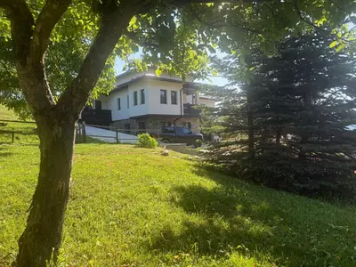 a house in a field with a tree in the foreground at Къща за гости МЕЧА СТЪПКА in Gela