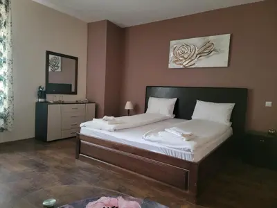 a bedroom with a large bed and a mirror at Стаи за гости Писателите in Hisarya