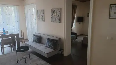 a living room with a white couch and a table at Стаи за гости Писателите in Hisarya