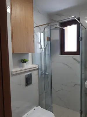 a bathroom with a toilet and a glass shower at Villa Vitosha Apartments in Hisarya
