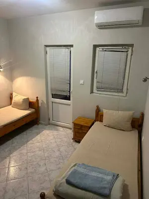 a small bedroom with two beds and a window at Хотел Елит in Kostinbrod