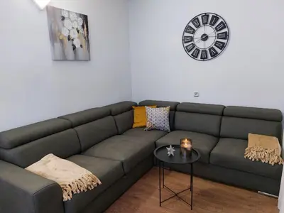 a living room with a couch and a clock on the wall at Tsvetanov Apartment in Blagoevgrad