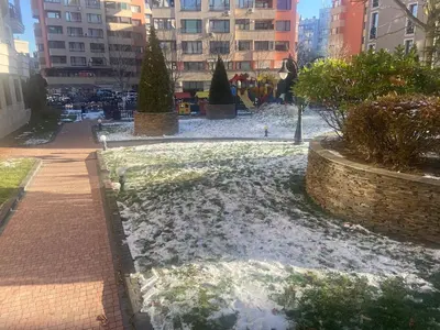 a park with snow on the ground and buildings at Blavka apartment Gardenia in Sofia