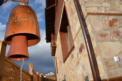 a large red bell hanging from the side of a building at Ognyanovata Guest House in Dobărsko