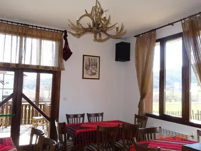 a dining room with a table and chairs and windows at Ognyanovata Guest House in Dobărsko