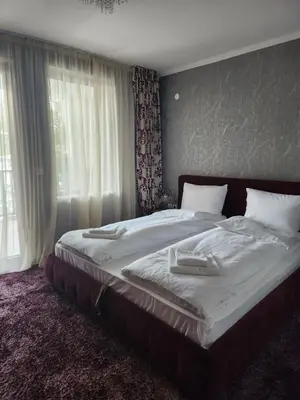 a large bed in a bedroom with a large window at Костадинов 1 in Pamporovo