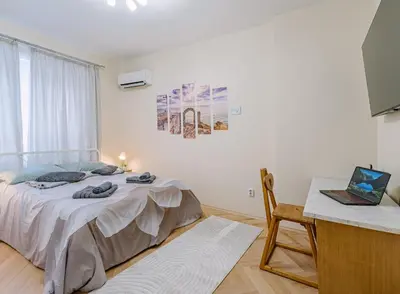 a bedroom with a bed and a desk with a laptop at Grand Luxury Condo by NDK and National Stadium with Free Parking in Sofia