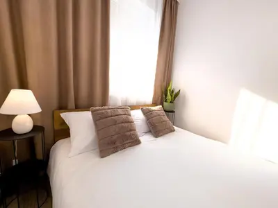 a bedroom with a white bed with a window at Serenity Apartment Bansko in Bansko