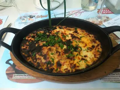 a pizza in a pan on a table at Sirius Apartment in Sofia
