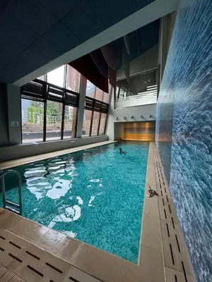 a large swimming pool with two people swimming in it at Maisonette Mountain View - Euphoria Resort in Borovets