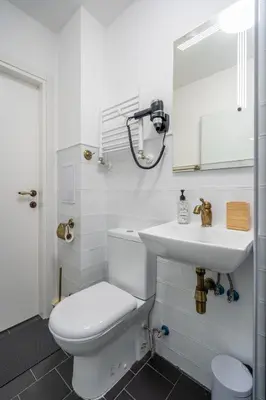 a white bathroom with a toilet and a sink at A central retreat in the heart of Sofia in Sofia