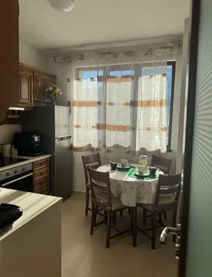 a kitchen with a table with chairs and a refrigerator at Апартамент Слънчев дом in Smolyan