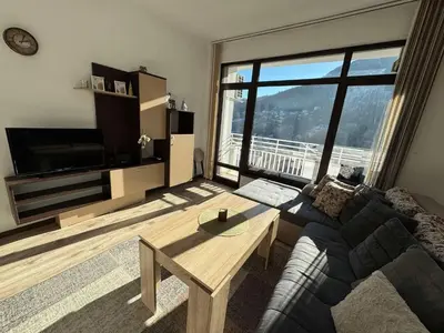 a living room with a couch and a large window at Апартамент Слънчев дом in Smolyan