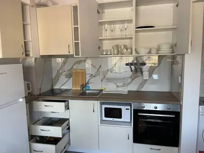 a kitchen with white cabinets and a sink and a microwave at Bansko soul relax place in Bansko