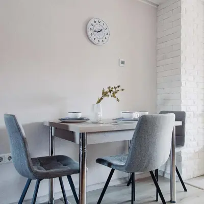 a dining room table with two chairs and a clock on the wall at Pirin Peaks Residence - next to Ski Lift in Bansko