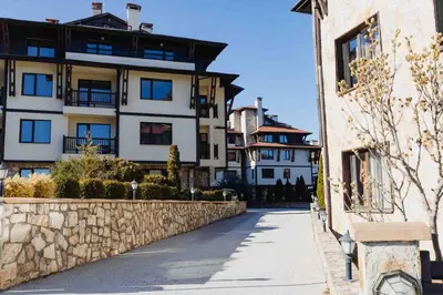 a building with a stone wall next to a street at Pirin Peaks Residence - next to Ski Lift in Bansko