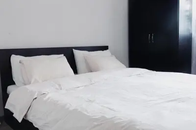 a large white bed with white sheets and pillows at Pirin Peaks Residence - next to Ski Lift in Bansko