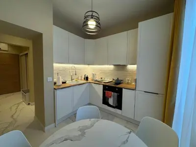 a kitchen with white cabinets and a table and chairs at Homely Apartment in Lozenets Sofia in Sofia