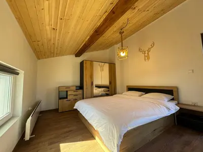 a bedroom with a large bed and a wooden ceiling at Вила Mountain Ship in Dedovo