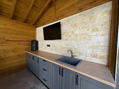 a kitchen with a sink and a tv on a wall at Вила Mountain Ship in Dedovo