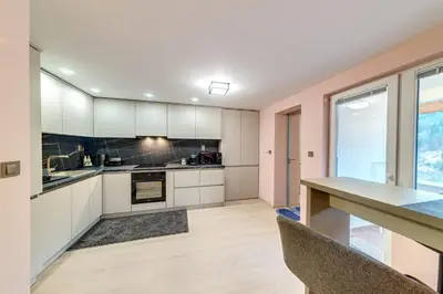 an empty kitchen with white cabinets and a table at Апартамент за гости Райково in Smolyan