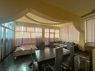 a dining room with a table and chairs and windows at arartment in Kostandovo