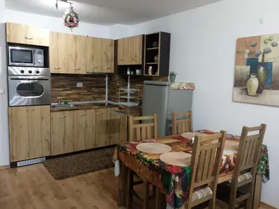 a kitchen with a table with chairs and a refrigerator at Двустаен апартамент 