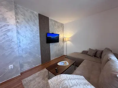 a living room with a couch and a tv on the wall at Host2U Belvedere Apartment - Ski in - out - FREE Parking in Bansko