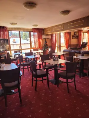 a restaurant with tables and chairs and a christmas tree at Снежна приказка Пампорово в хотел Mountain Lodge ап 29 in Pamporovo
