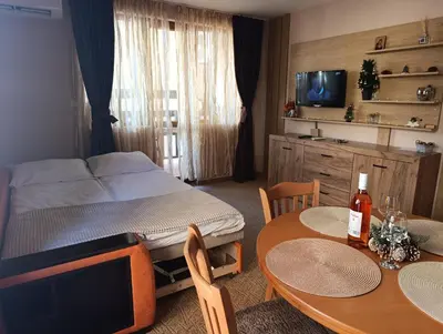 a bedroom with a bed and a table with two chairs at Снежна приказка Пампорово в хотел Mountain Lodge ап 29 in Pamporovo