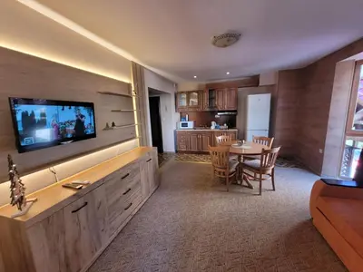 a living room with a television and a table with chairs at Снежна приказка Пампорово в хотел Mountain Lodge ап 29 in Pamporovo