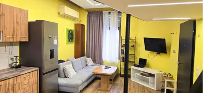 a living room with a couch and a tv at Tranquility Lodge, next to Paradise and metro station in Sofia