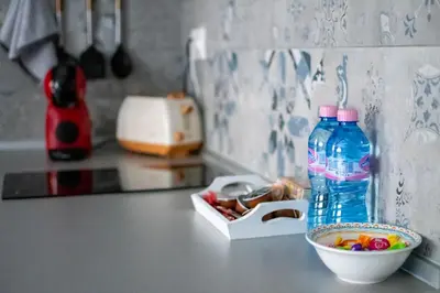 a bottle of water sitting on a counter next to a bowl of candy at HD Comfort Apartment in Sofia