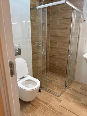 a bathroom with a toilet and a glass shower at Pana Green Residence in Panagyurishte