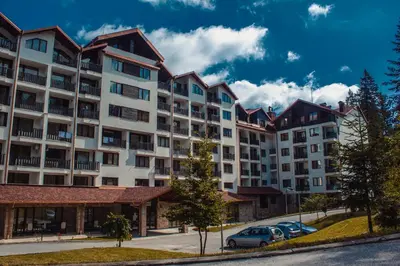 a large apartment building with cars parked in a parking lot at Borovets Gardens Aparthotel Seasons Borovets PM in Borovets